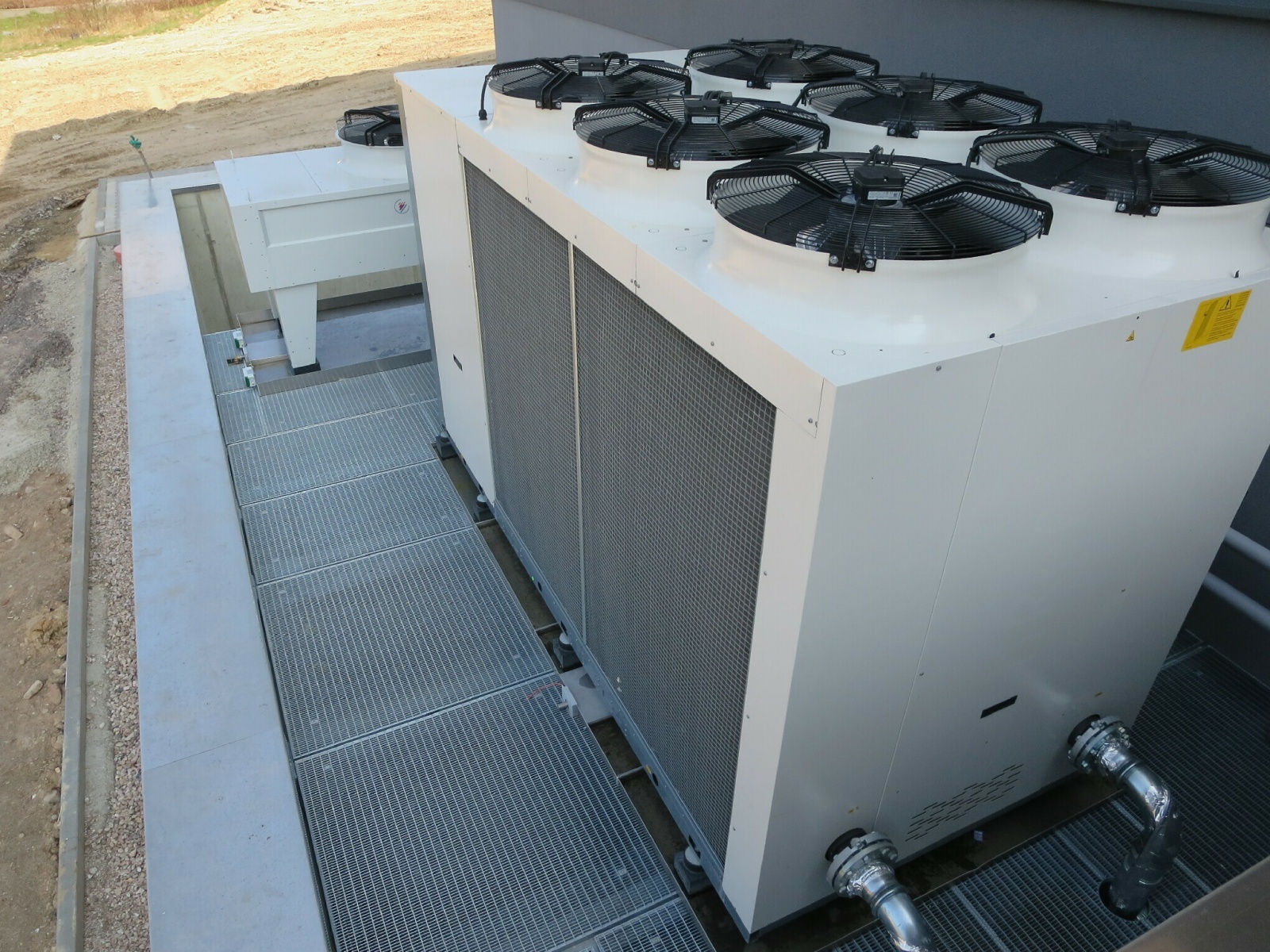 Produktionsstätte LCP, reversible Wärmepumpe zur Wärme- oder Kälteenutzung (Front) + Rückkühler zur Wärmeabfuhr und Freikühlung (Hinterseite); aufgestellt auf Gitterrost über dem Fortluftkanalauslass, Bild: Tom Lattermann